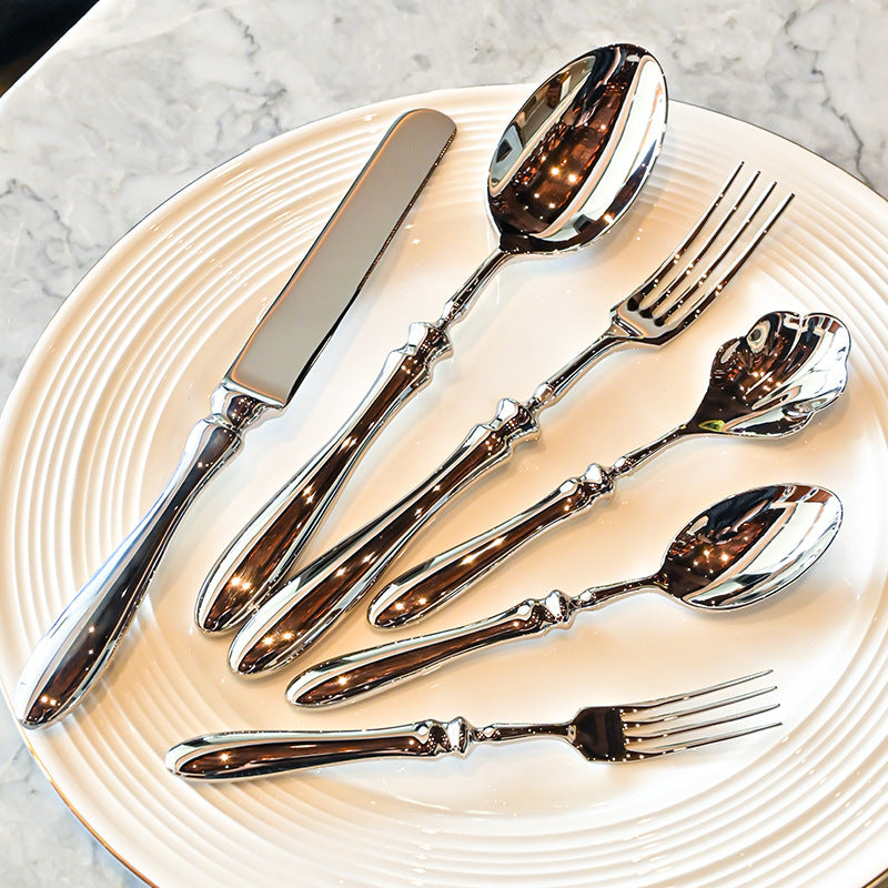 Silver cutlery set on a white plate with a marble background