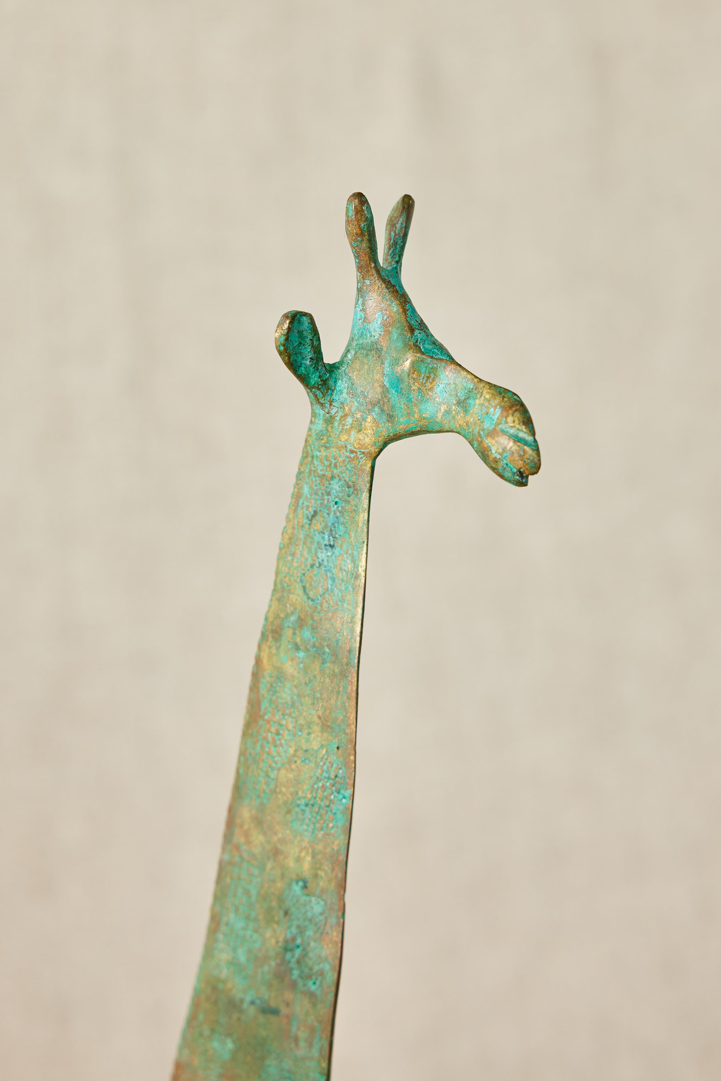 Close up of a brass giraffe figurine on a beige background