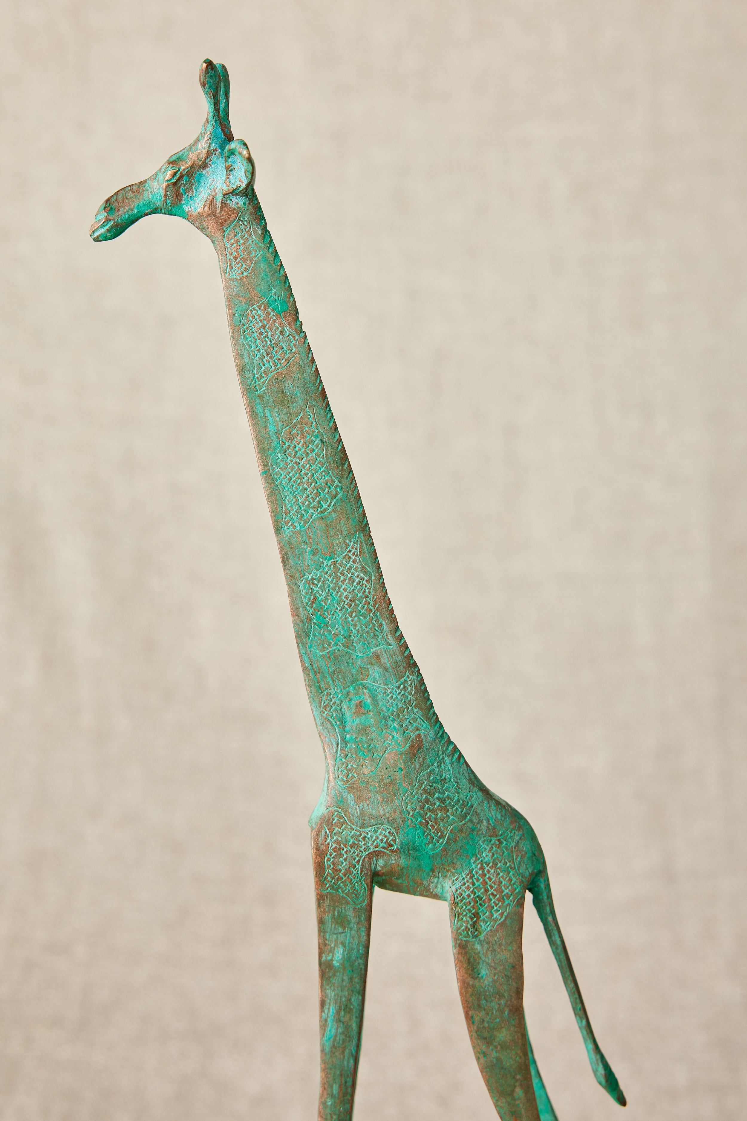 Brass giraffe sculpture on a beige background