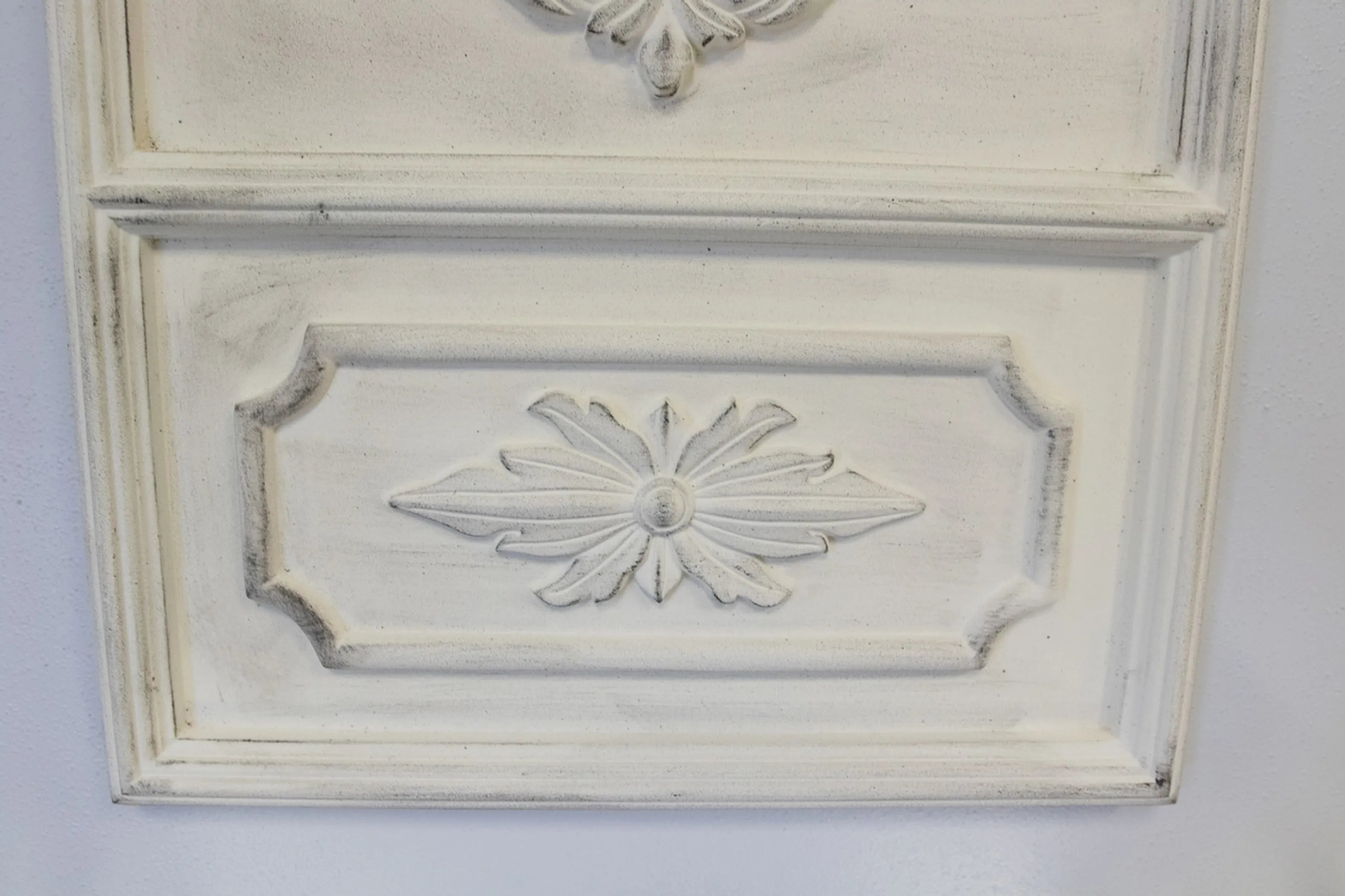 Close up of intricate carving on a Angelique French Trumeau Stone White Wall Mirror on a light gray background