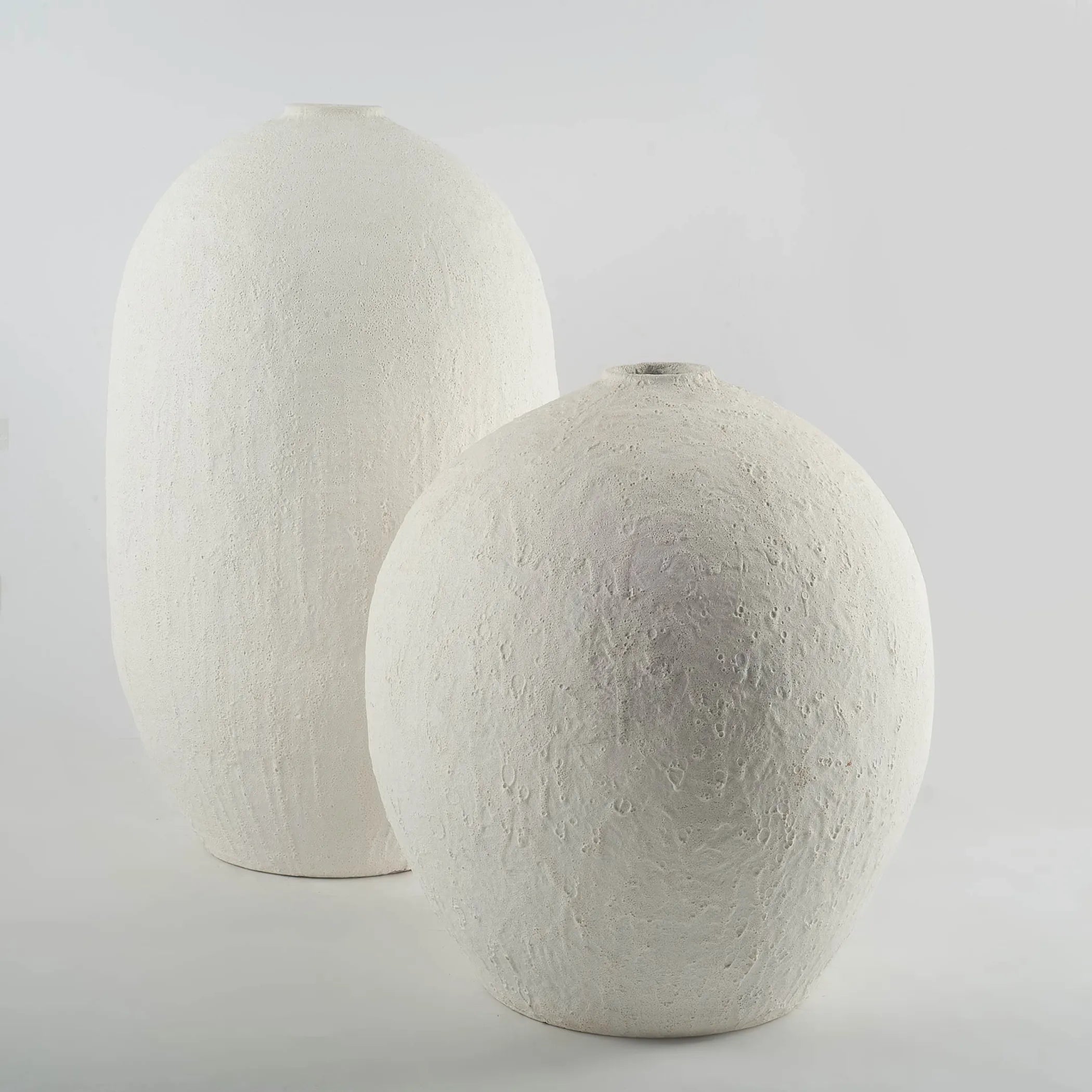Two textured white ceramic vases on a light gray background