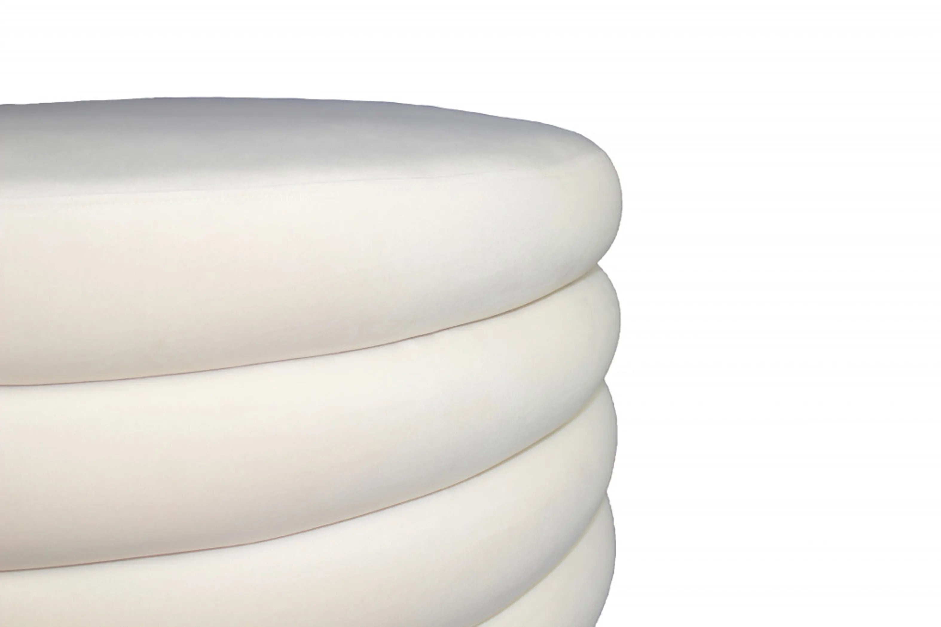 Close up of a white velvet cylindrical ottoman on a white background
