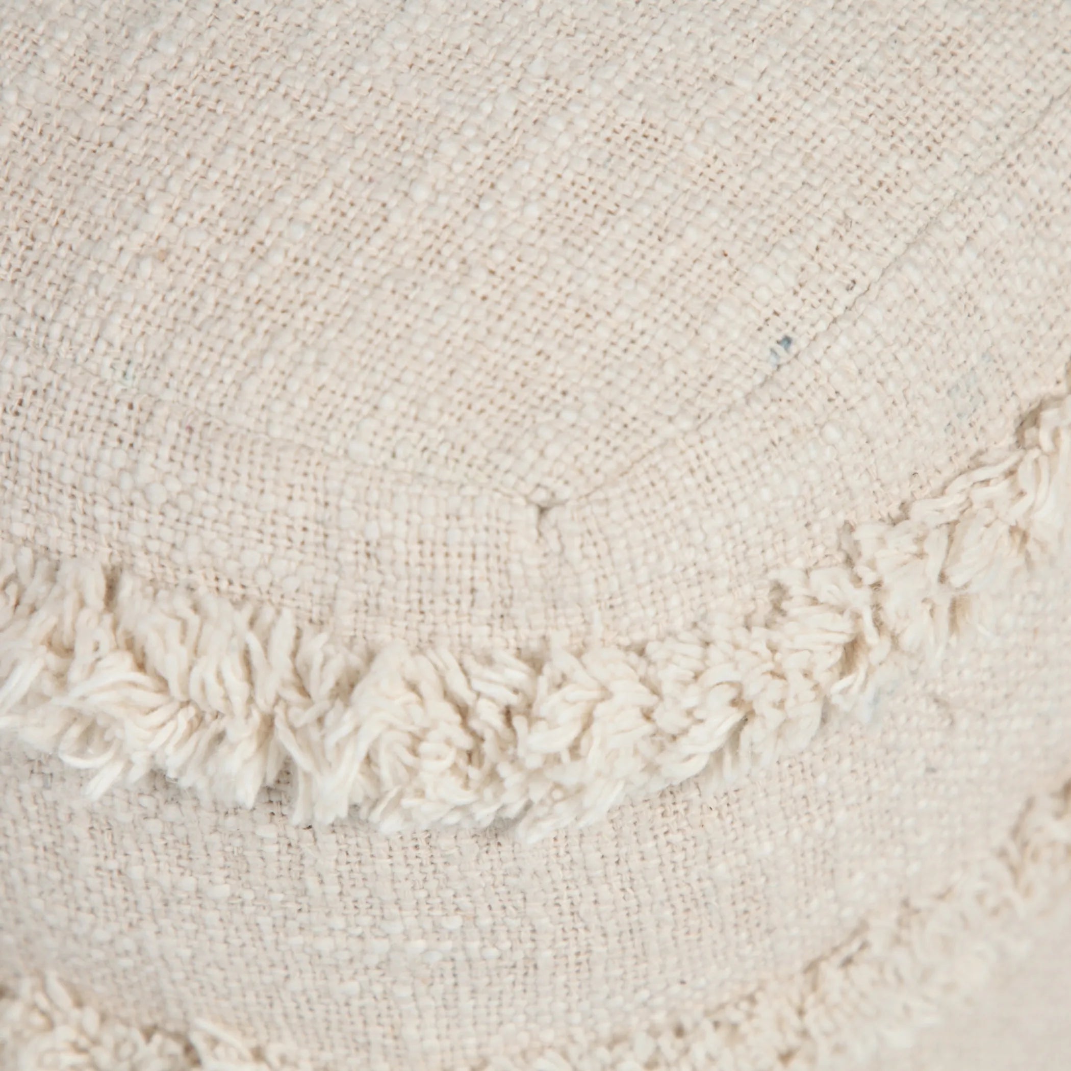 Close-up of textured fabric on an ottoman with fringe trim