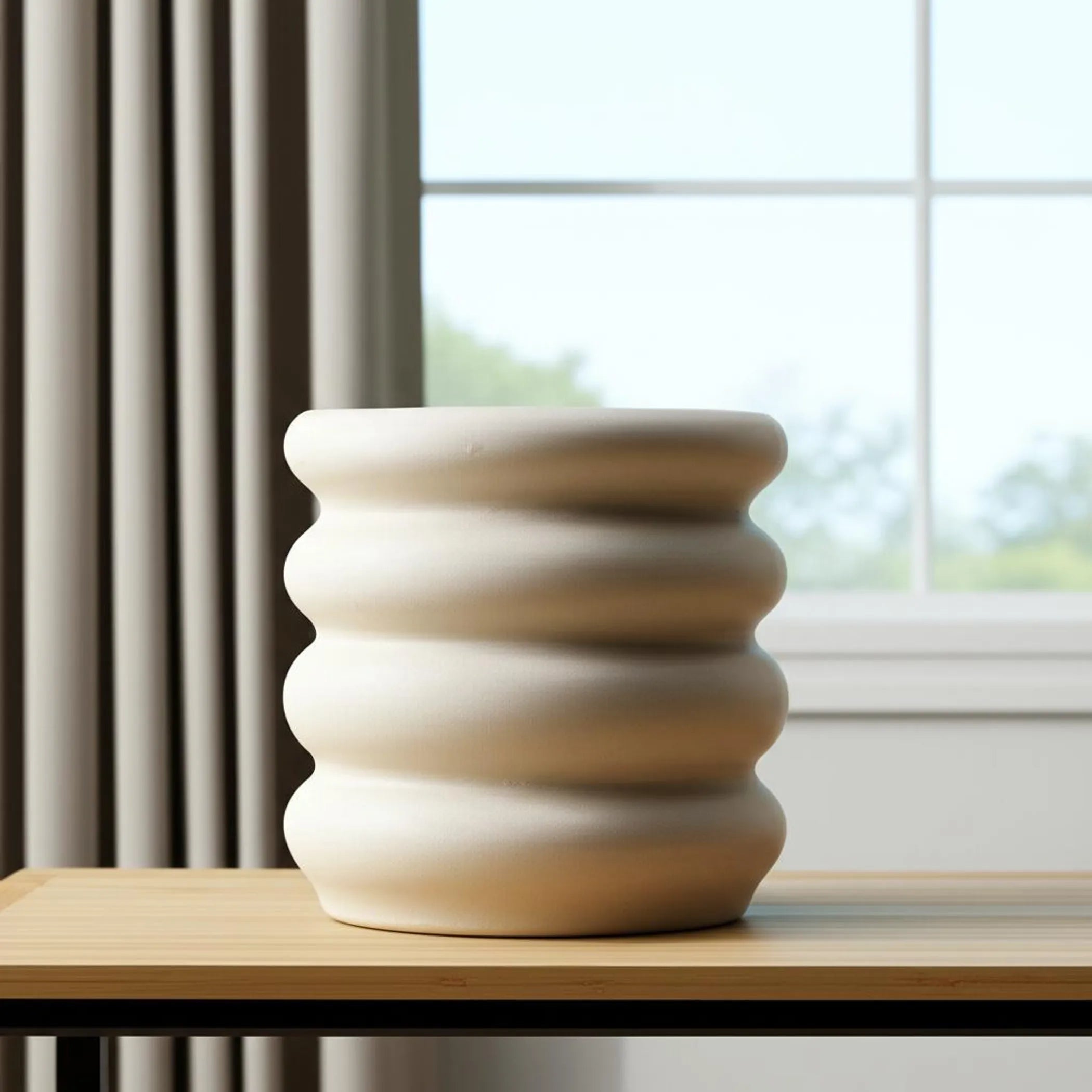 White ceramic vase with ribbed texture on a wooden surface with a window in the background