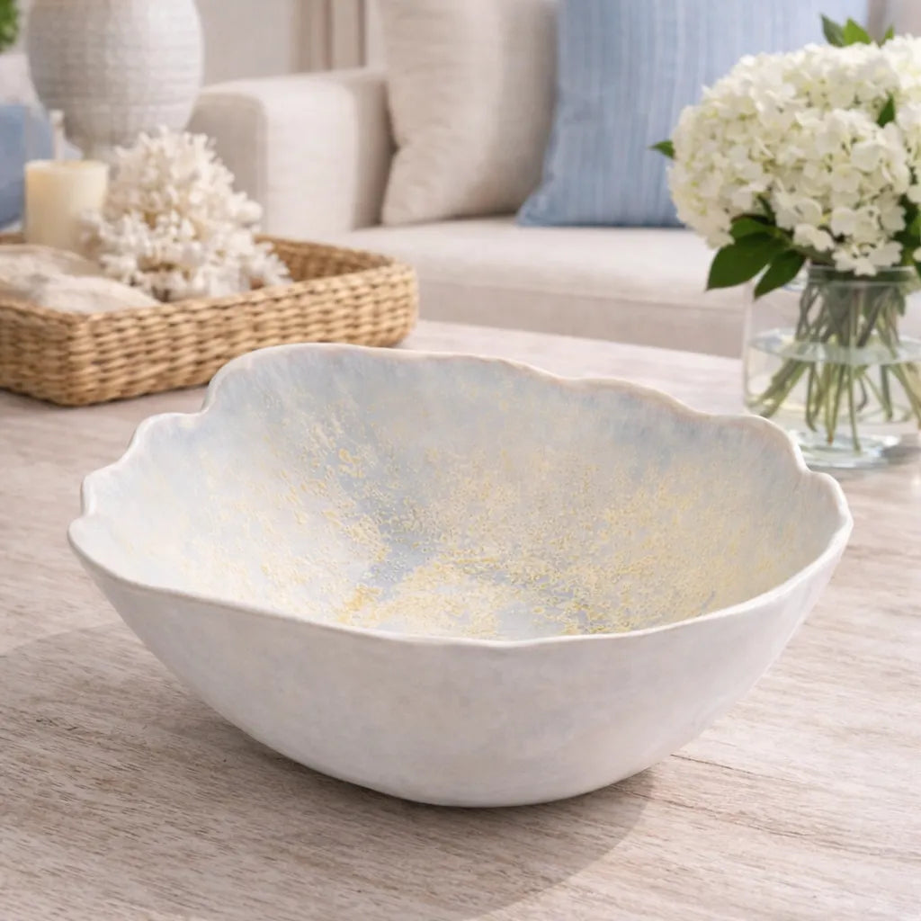 White decorative pearl oyster bowl on a wooden surface with flowers and candles in the background