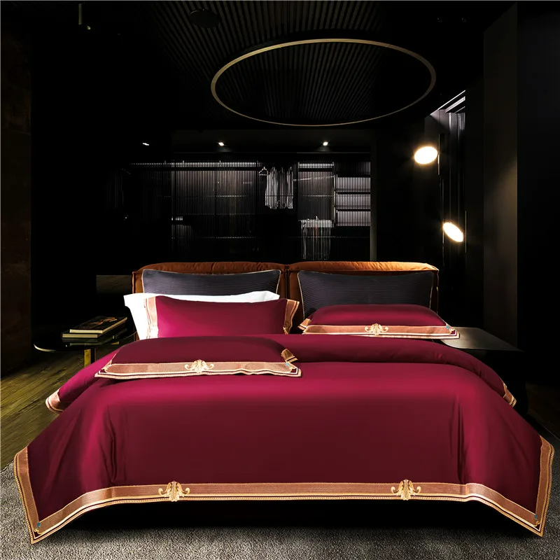 Luxurious bed with red bedding and gold accents in a darkly decorated room.