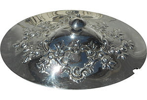 Silver cymbal with decorative patterns on a plain background