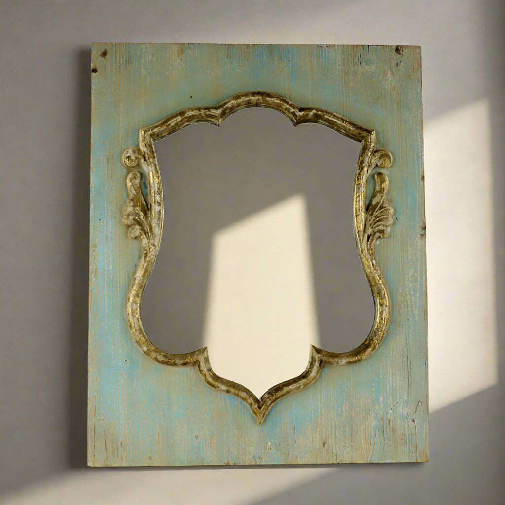 Decorative antique style shield shaped mirror with ornate frame on a textured wall