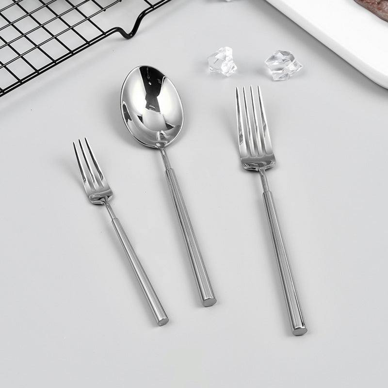 Set of silver cutlery including a spoon and two forks on a light gray surface.