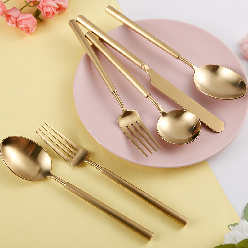 Gold cutlery set on a pink plate with flowers on a yellow background