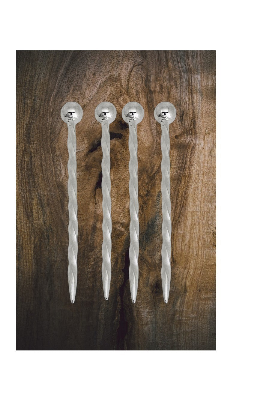 Four silver plated martini cocktail sticks on a wooden background