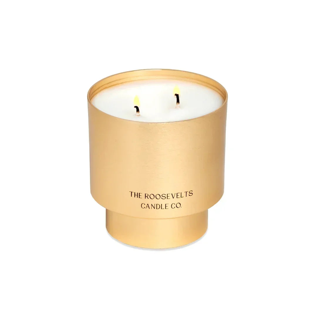 Gold candle holder with a lit candle inside on a white background