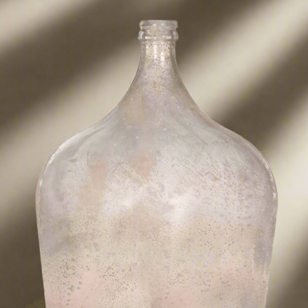 Clear glass bottle with a textured surface on a neutral background
