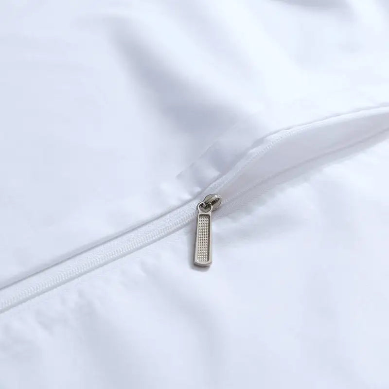 Close-up of a zipper on a white garment with a metal pull tab.