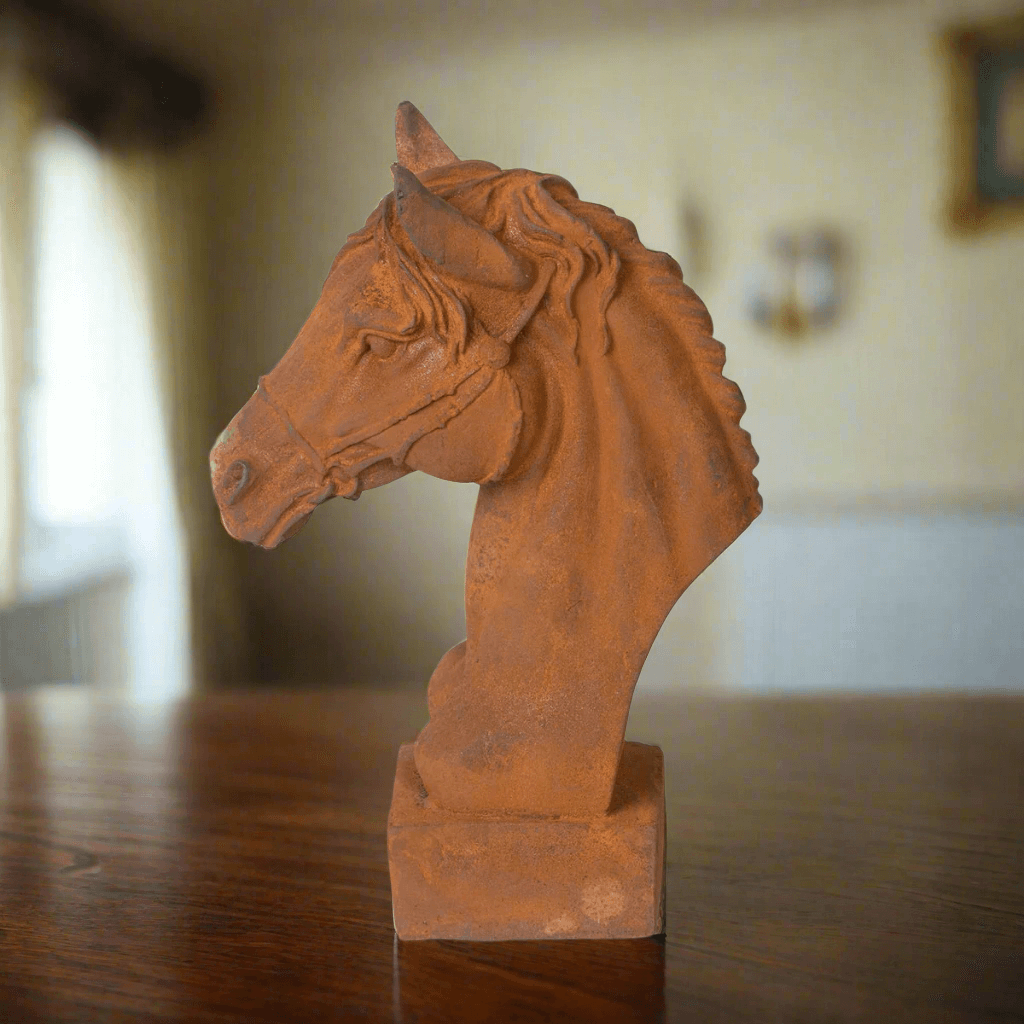 Terracotta horse head sculpture on a wooden surface with a blurred background