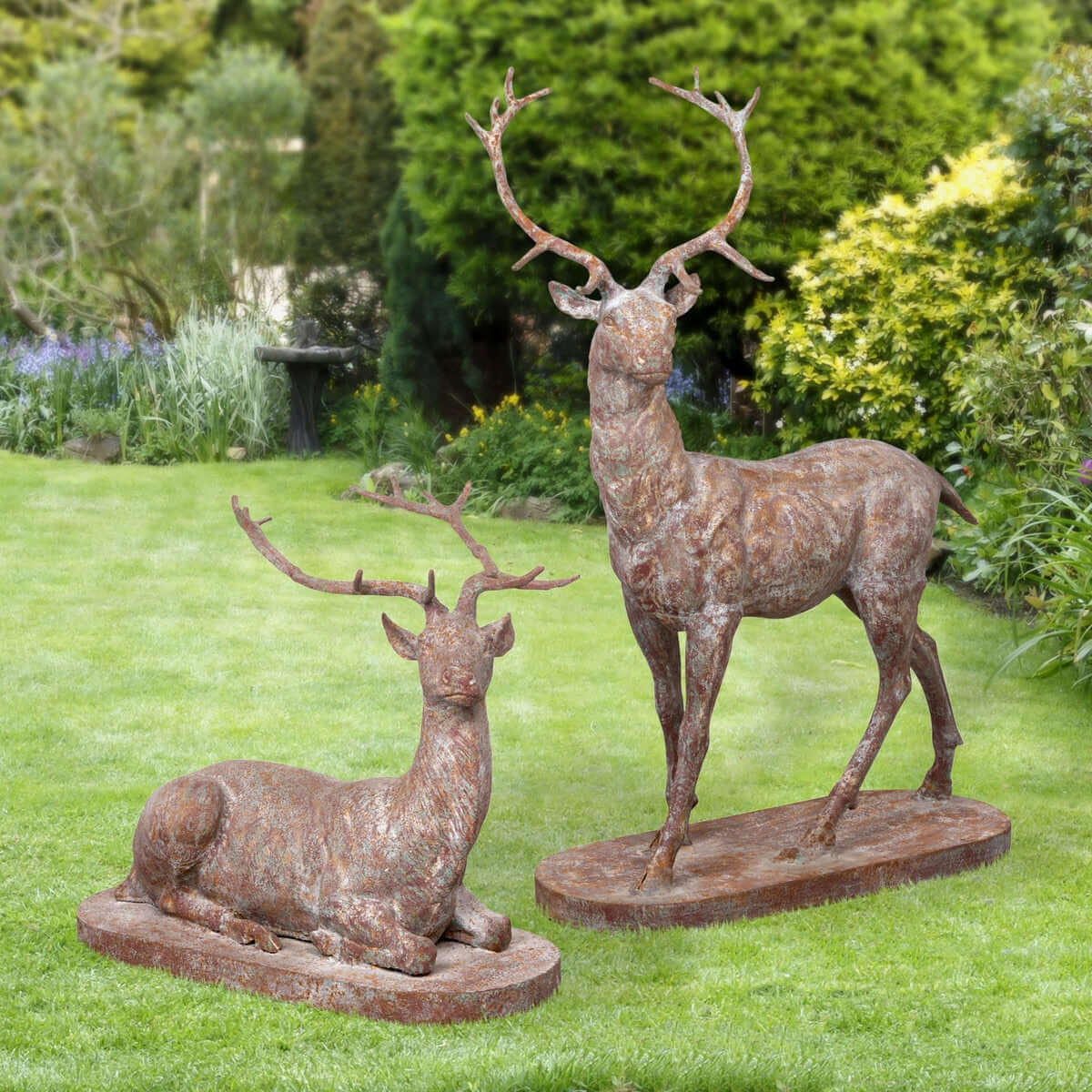 Two bronze deer statues on a grassy lawn with greenery in the background