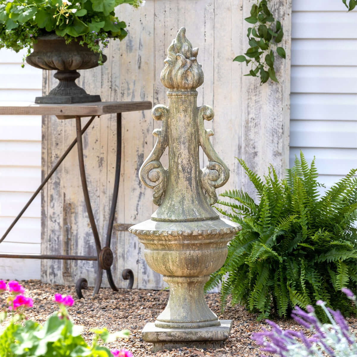 Decorative Grecian Garden Torch Statue with plants and flowers in a garden setting