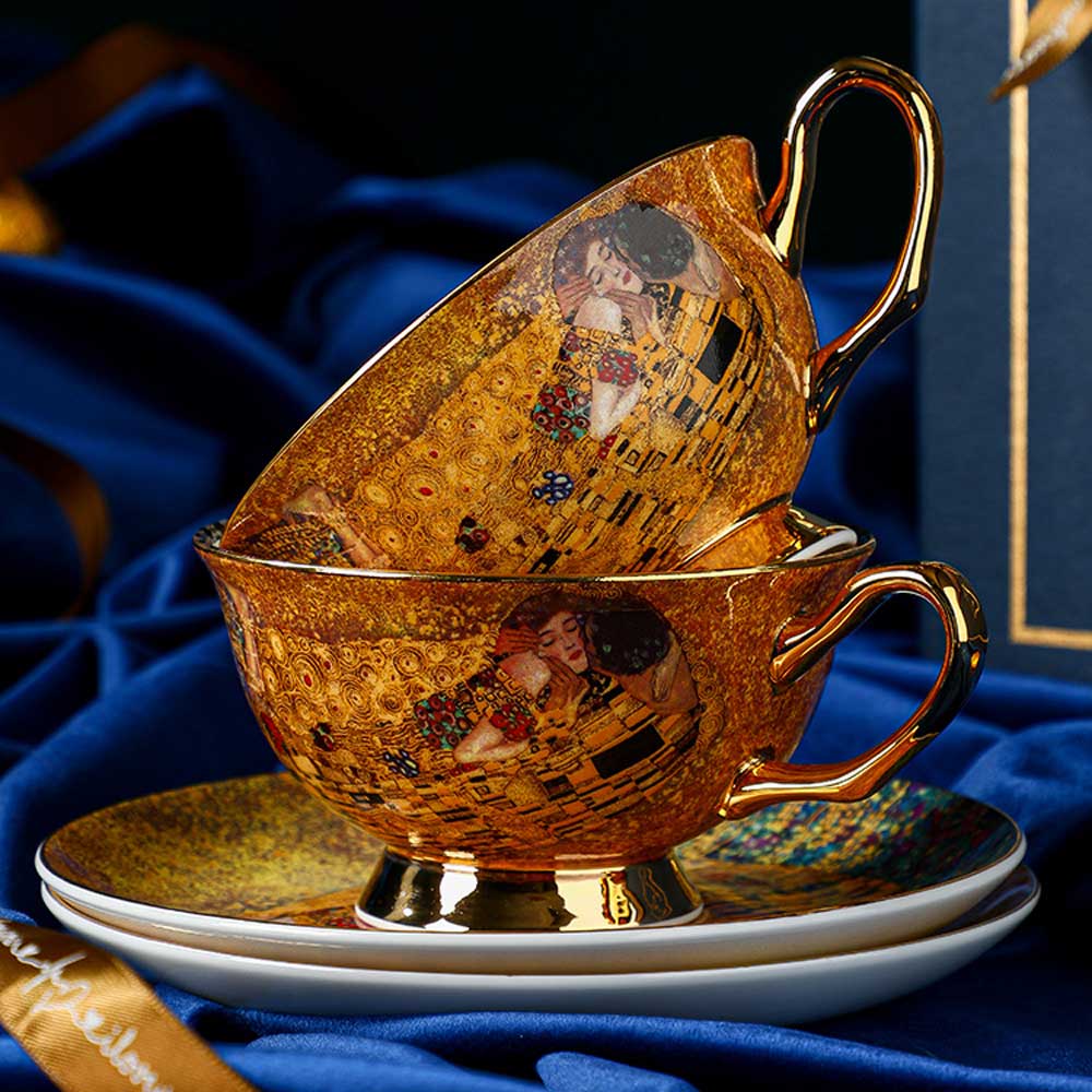 Decorative teacup and saucer set with artistic design on a blue fabric background