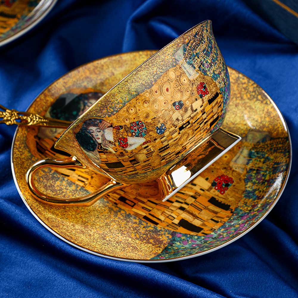 Decorative teacup and saucer with artistic design on a blue fabric background