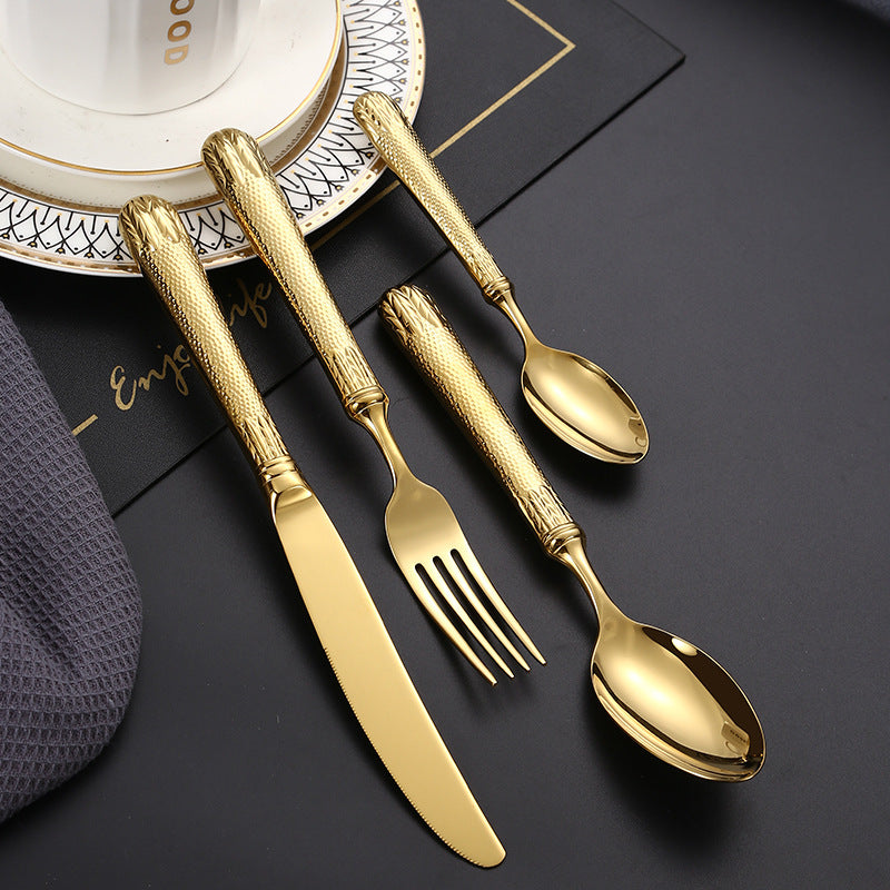 Set of gold cutlery including knife, fork, and spoons on a dark surface.