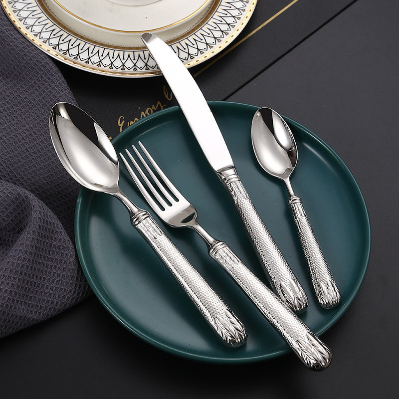 Silver cutlery set on a dark green plate with a decorative background