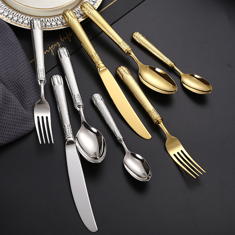 Set of silver and gold flatware on a dark surface