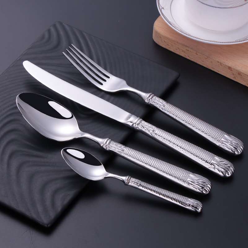 Set of silver cutlery including knife, fork, and spoons on a dark surface.