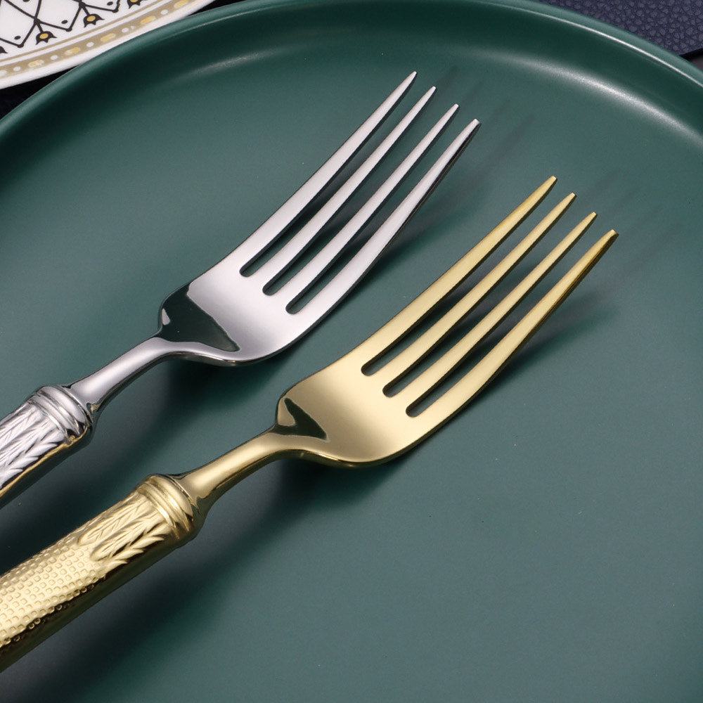 Two forks, one gold and one silver, on a green plate.