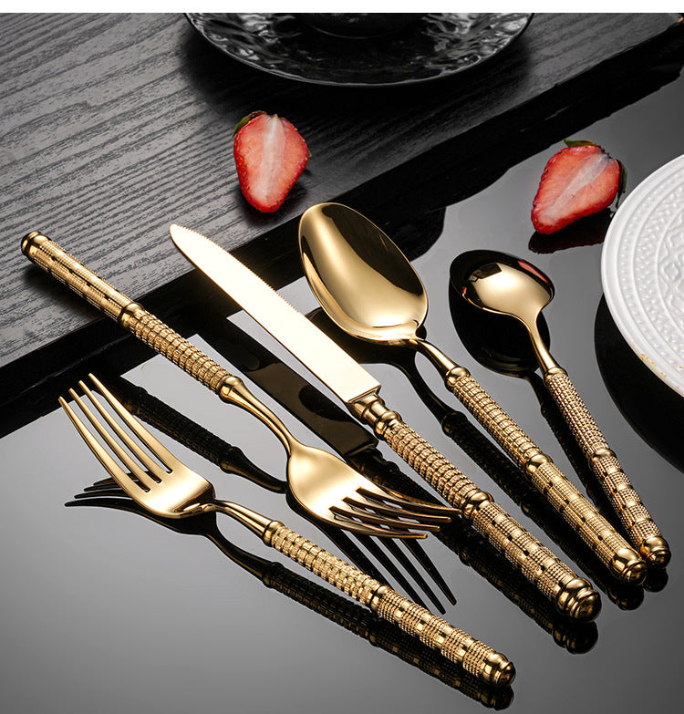Gold cutlery set on a dark surface with strawberries