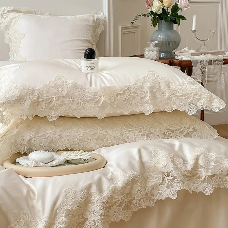 White lace bedding set on a bed with a small table and decorative items in the background.