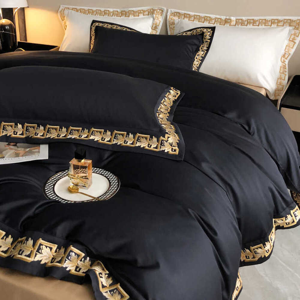 Black bedspread with gold embroidery on a bed in a bedroom setting.