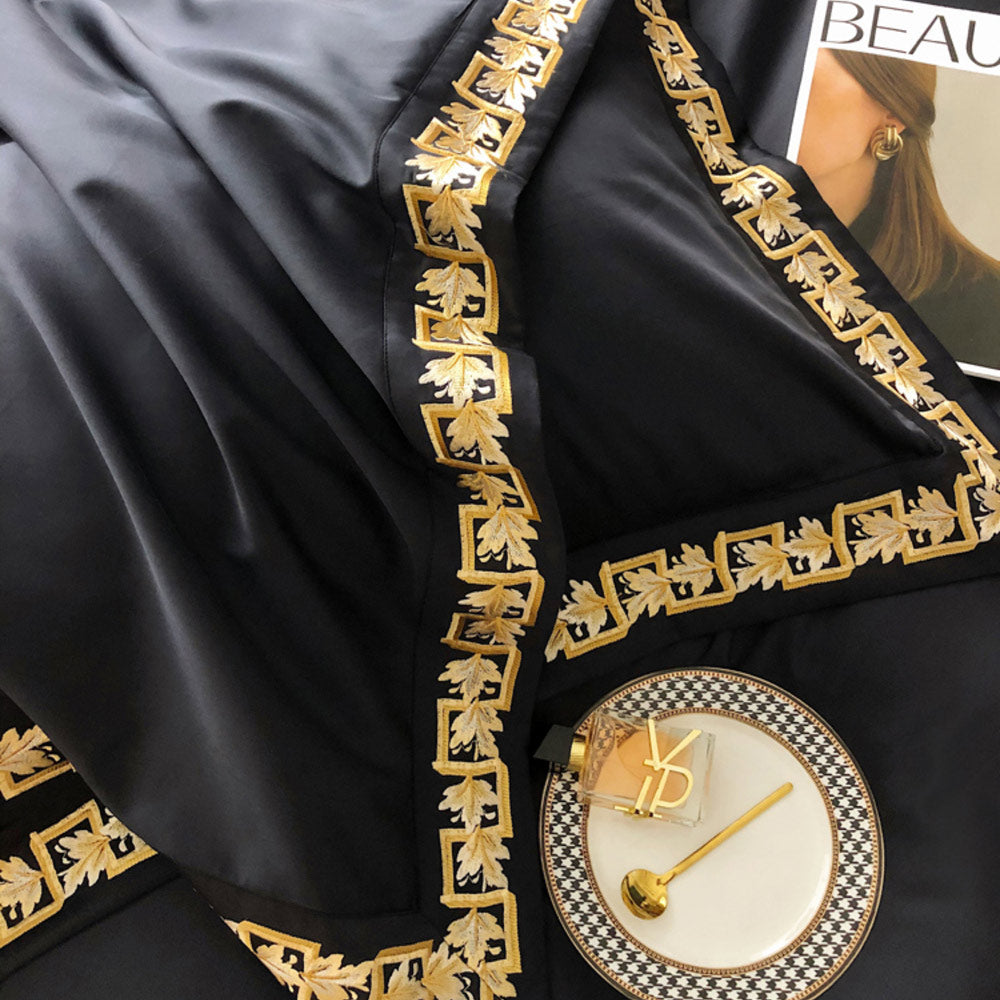 Black fabric with gold embroidery, YSL perfume bottle on a checkered plate.