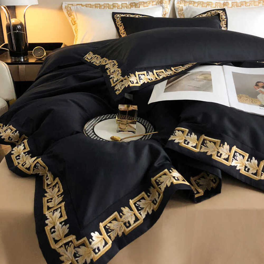 Black embroidered bedding set on a bed with a lamp and books in the background.