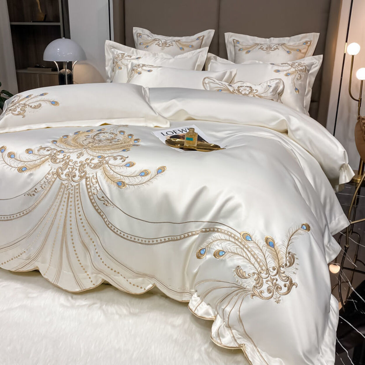 Luxurious white bedspread with gold embroidery on a bed in a bedroom setting.