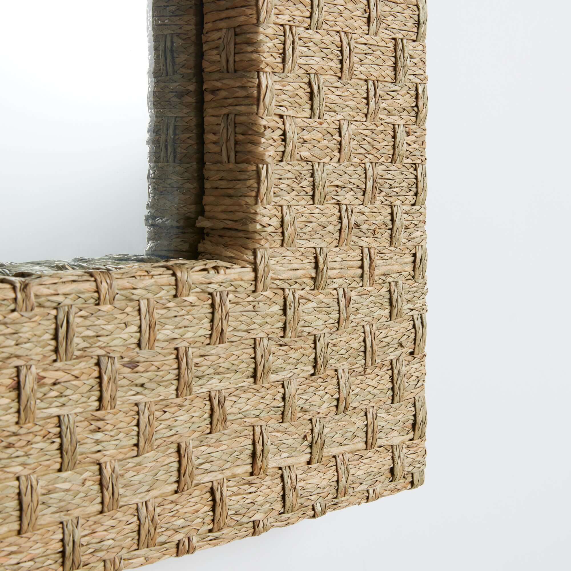 Close up of a Woven seagrass mirror on a white background