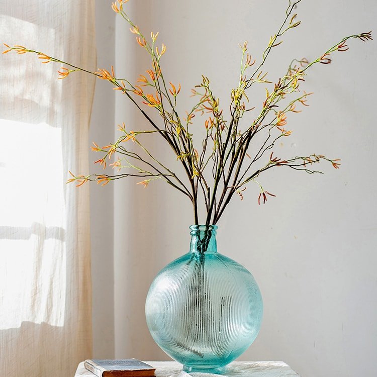 Blue glass vase with decorative branches on a white surface