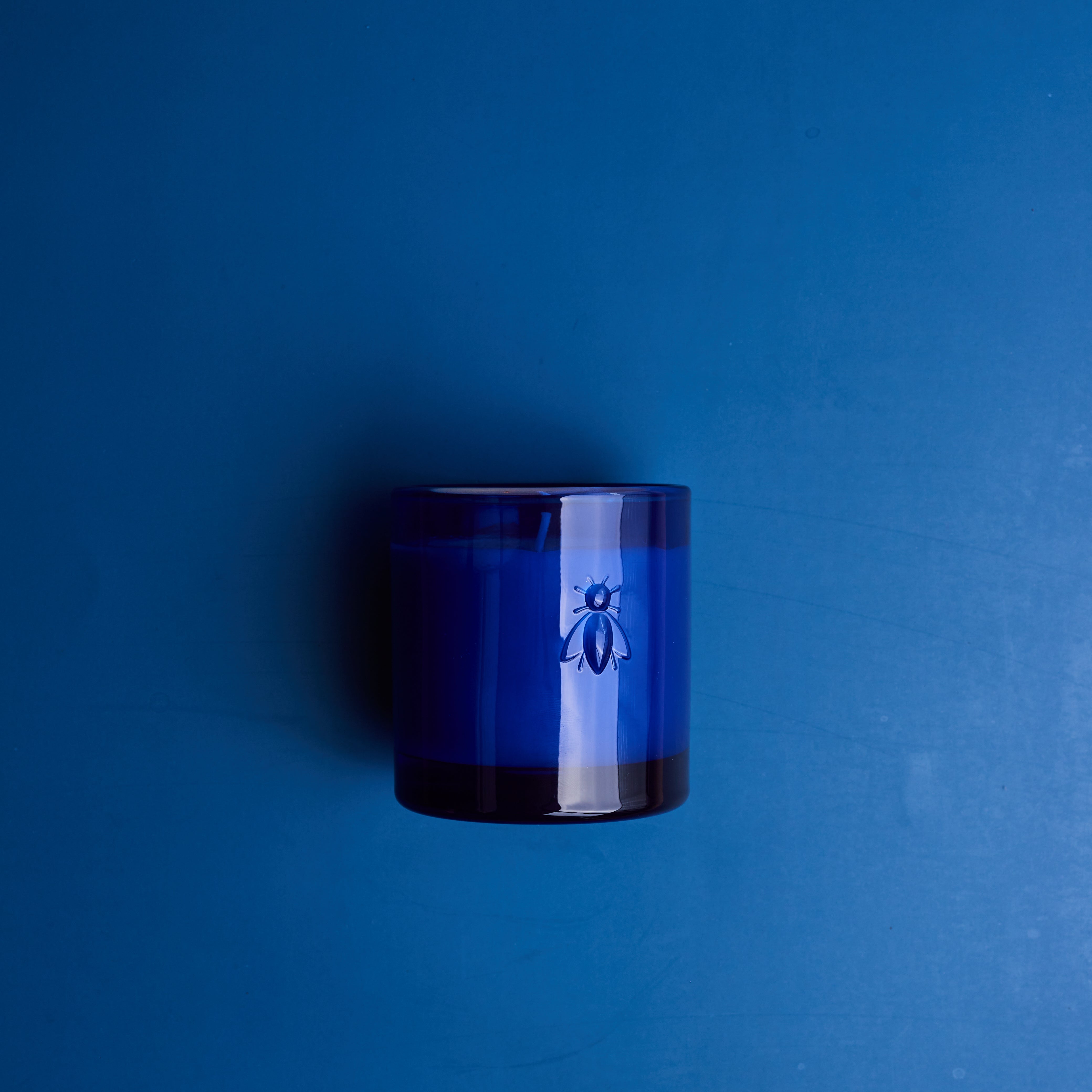 La Rochere candle in a Blue glass container with a bee logo on a blue background