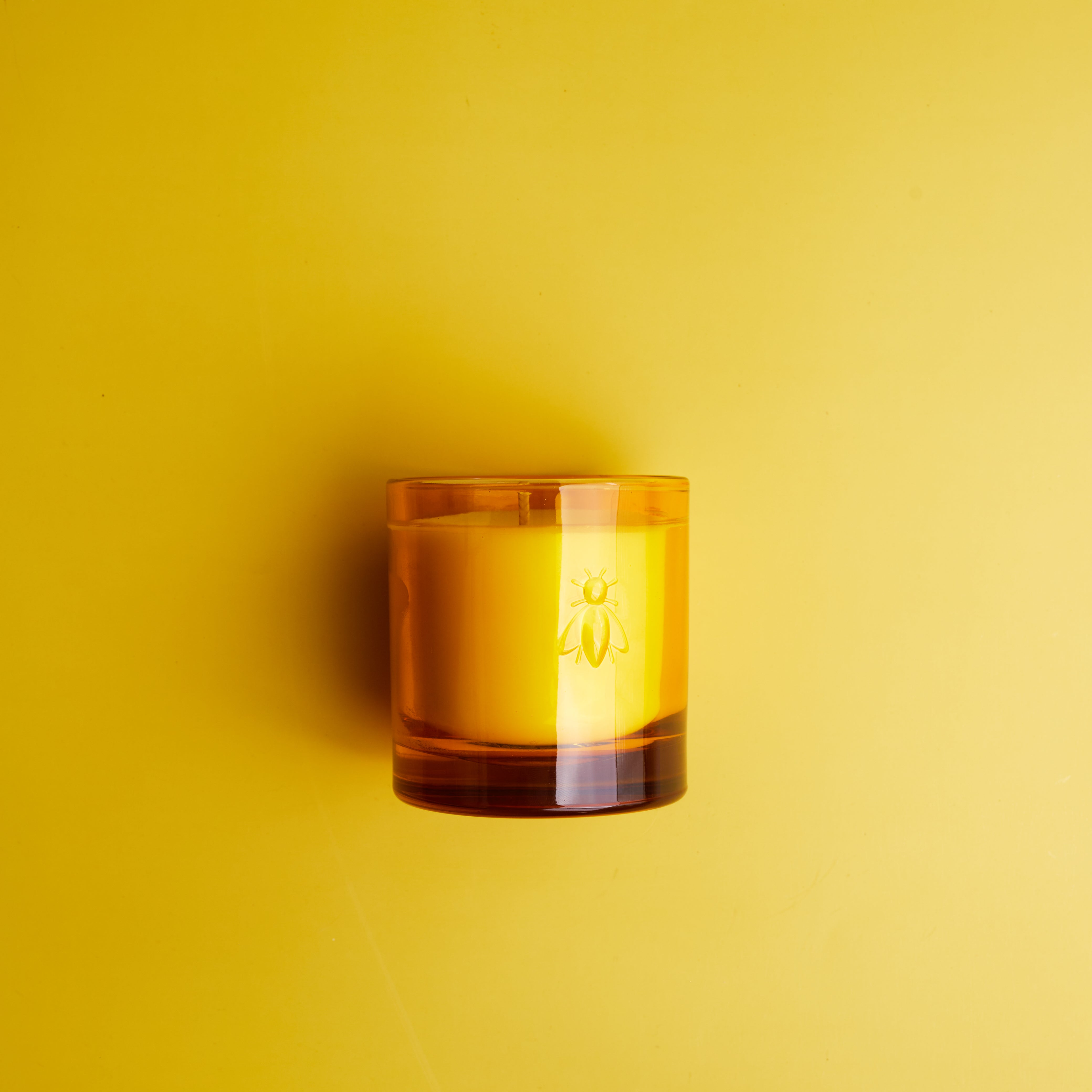 La Rochère Amber glass candle on a yellow background