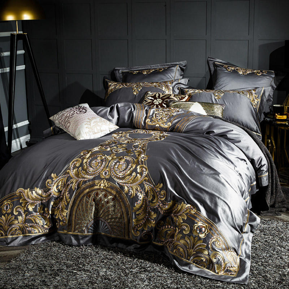 Luxurious gold and gray bedding set on a bed with a dark wall background.