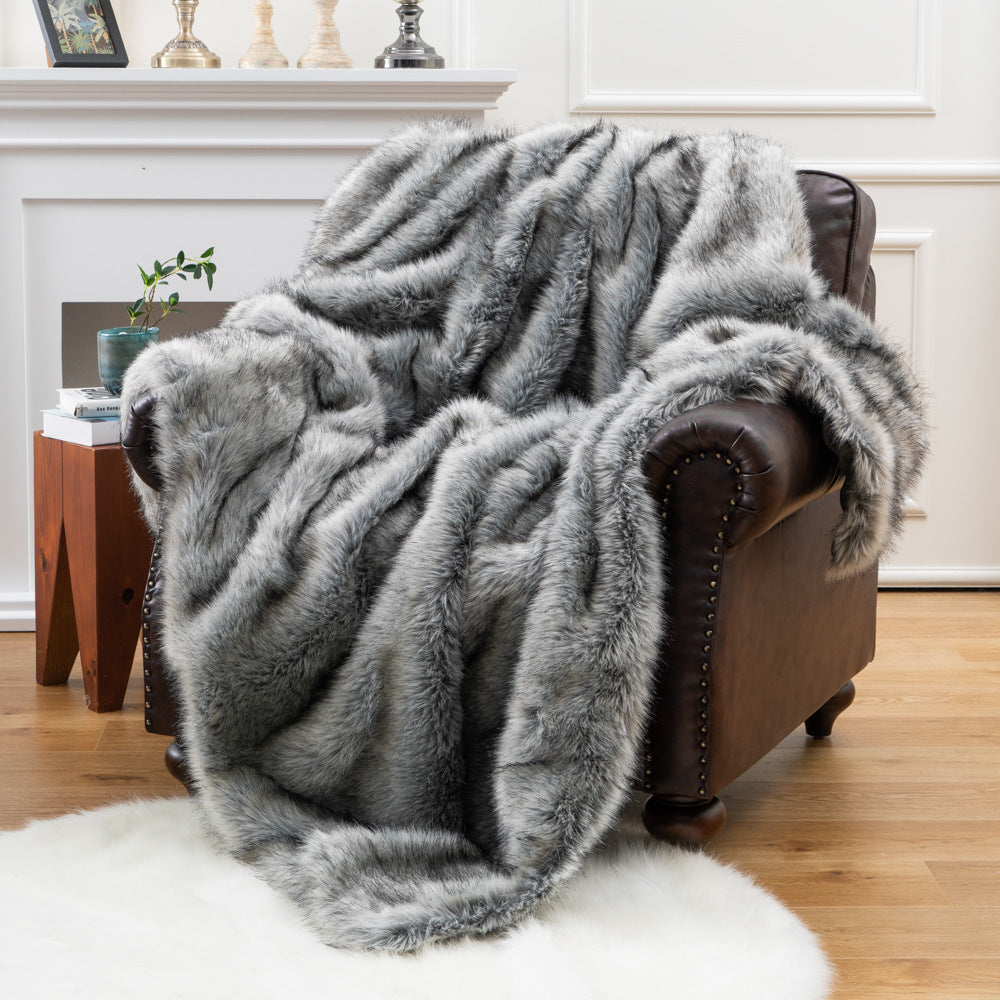Gray fur throw blanket draped over a brown leather armchair in a living room setting.