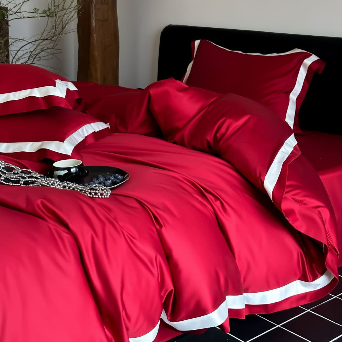 Red bedspread with white trim on a bed in a room.