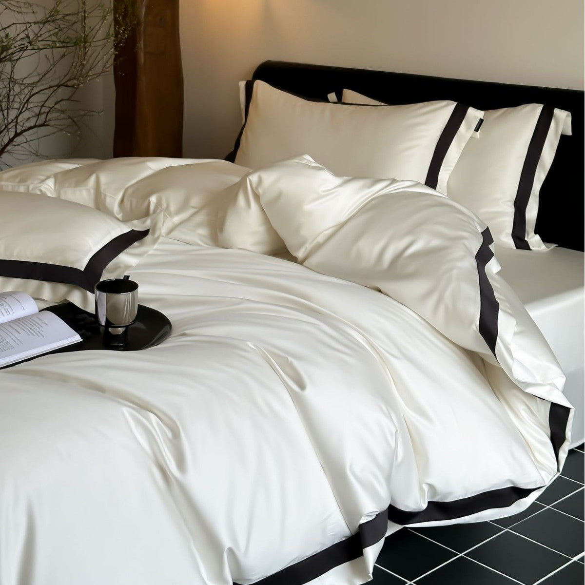White bedding set with black trim on a bed in a bedroom setting.