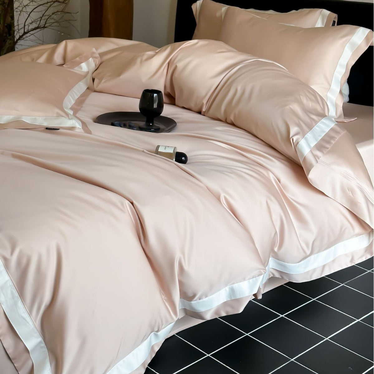 Beige bedspread with white trim on a bed in a room with tiled flooring.