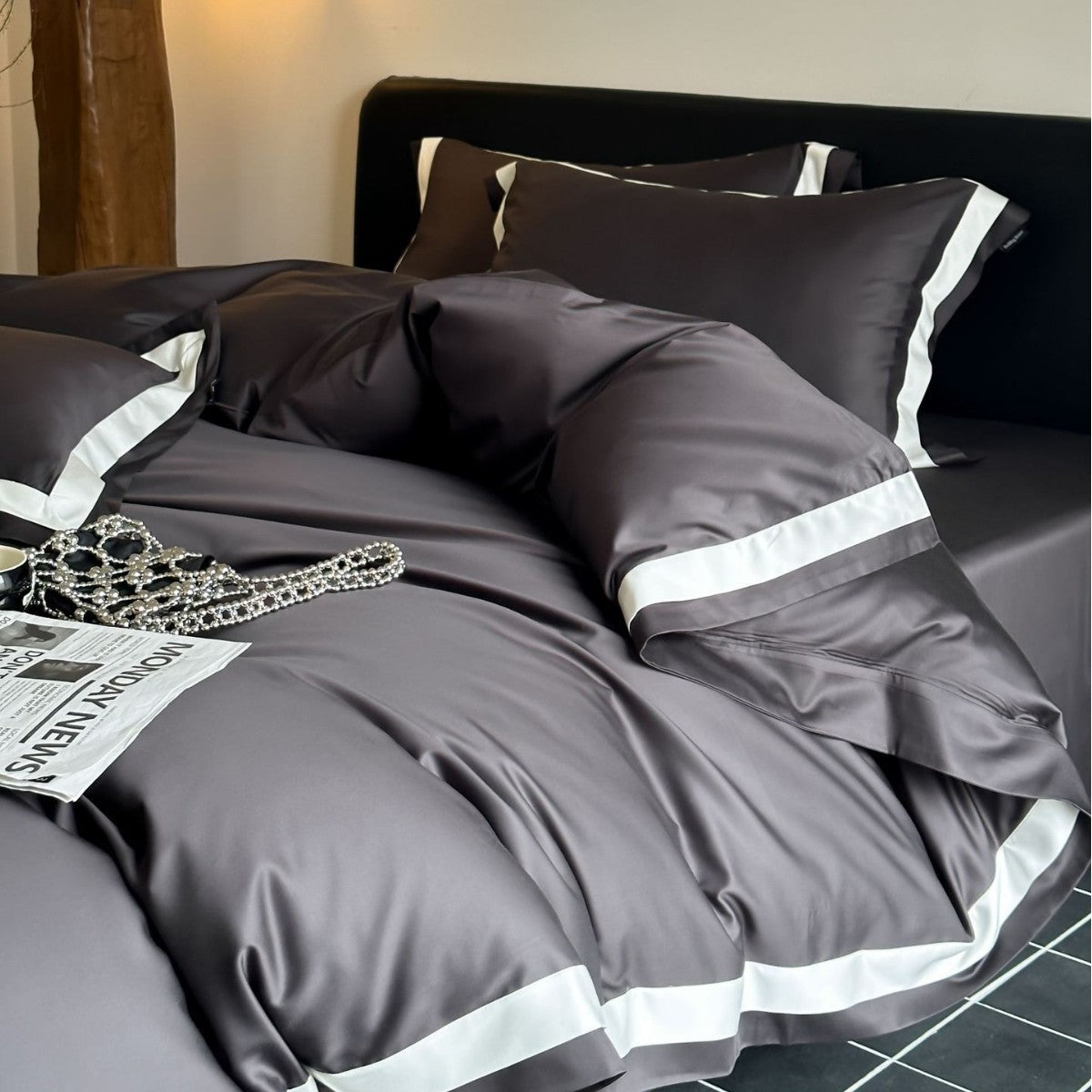 Gray bedding set with white stripes on a bed with a black headboard.