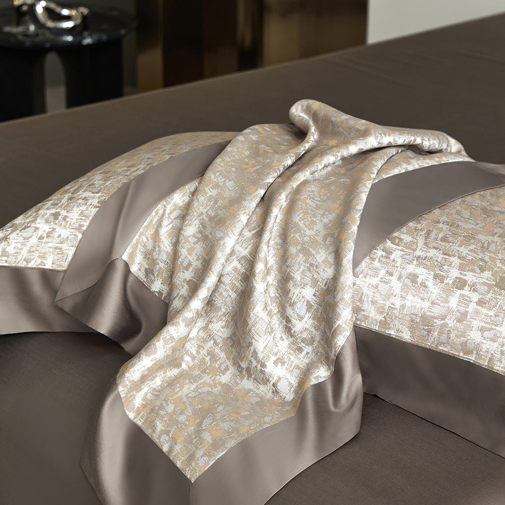 Decorative blanket with intricate pattern draped over a bed with matching bedding.
