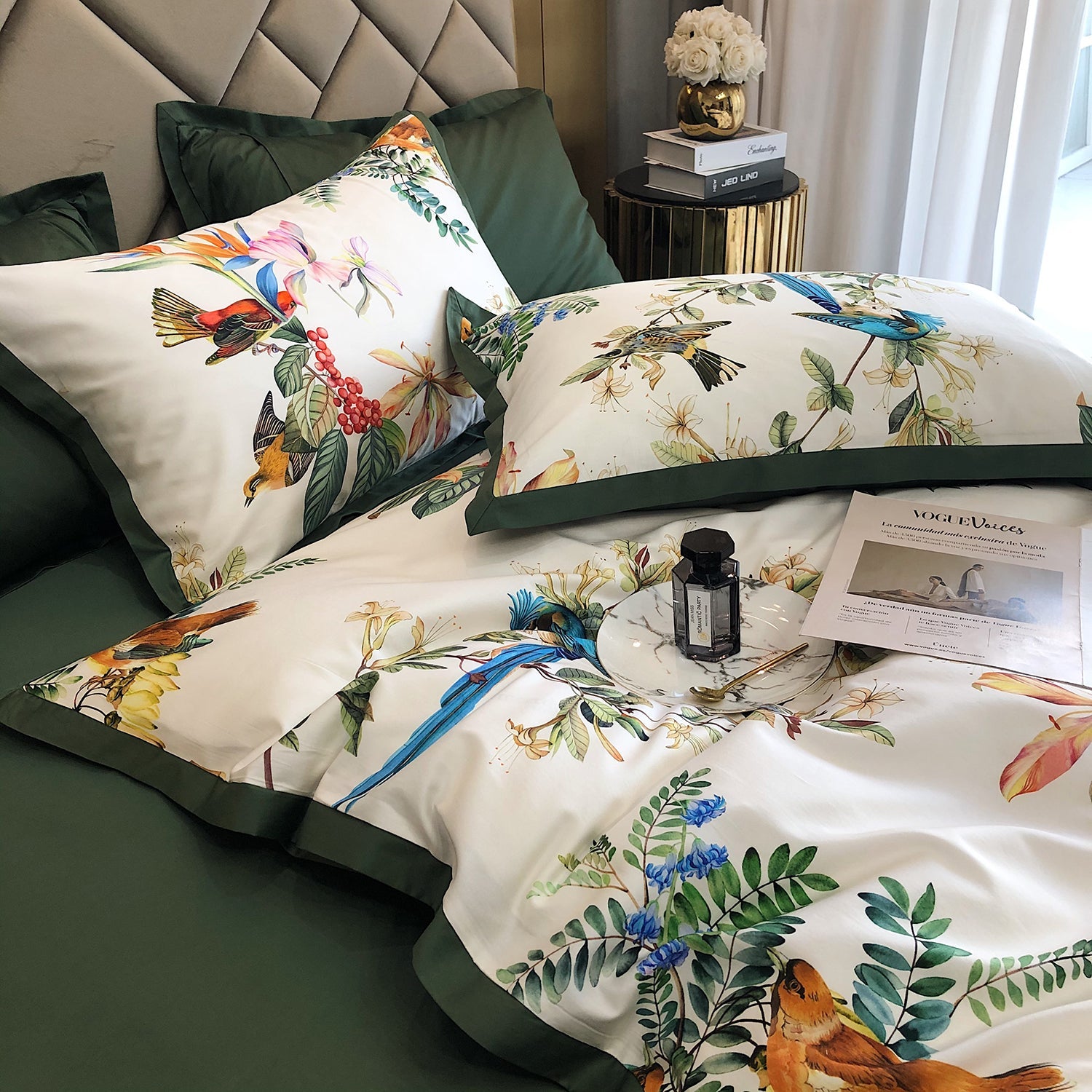 Floral and bird patterned bedding set on a bed with decorative pillows and a small table.