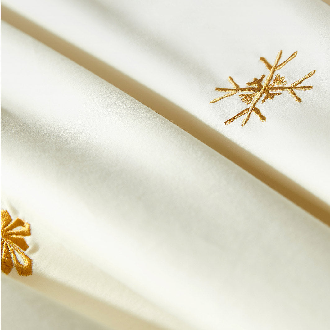 White fabric with gold embroidered snowflake patterns
