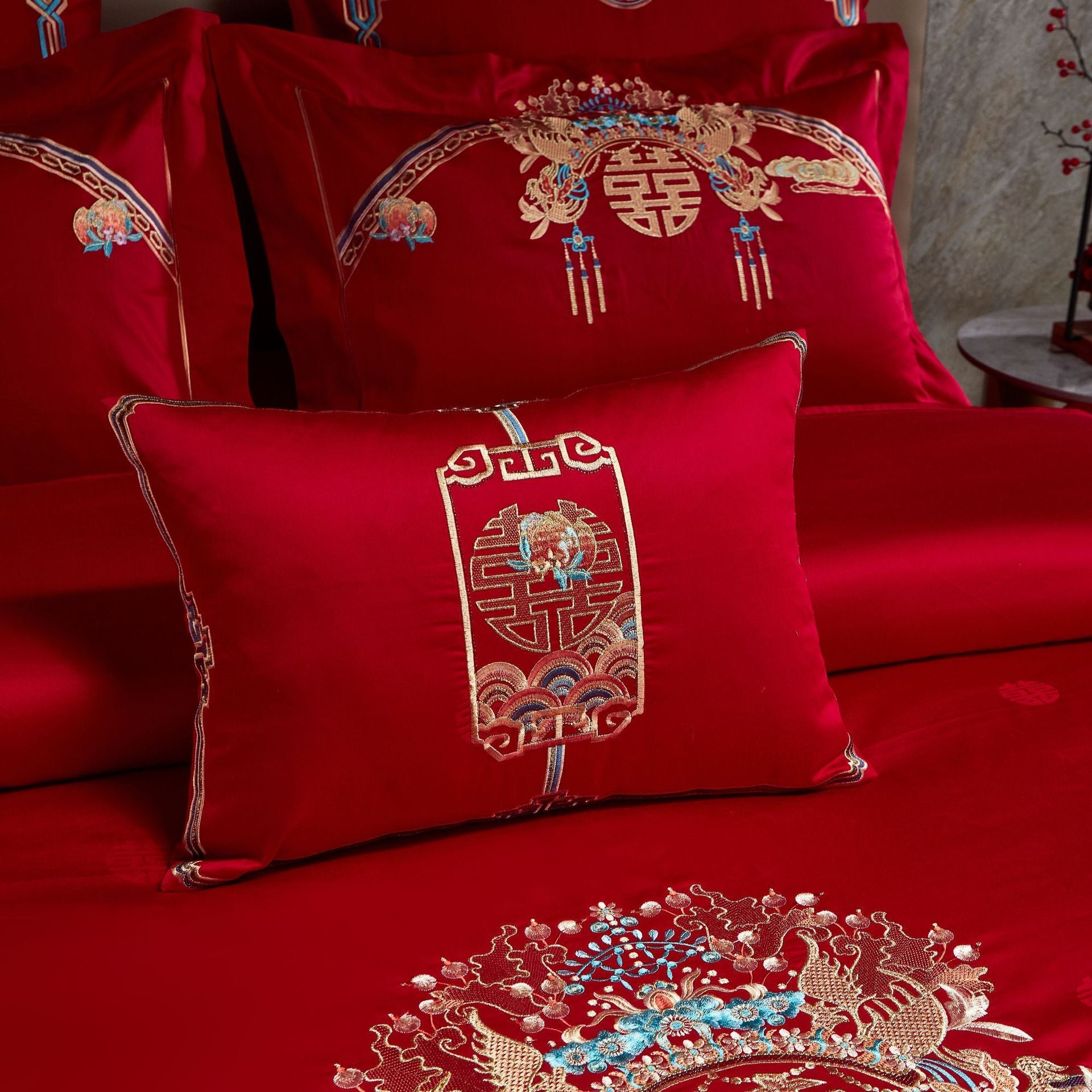 Red embroidered bedding set with intricate patterns on a stone wall background
