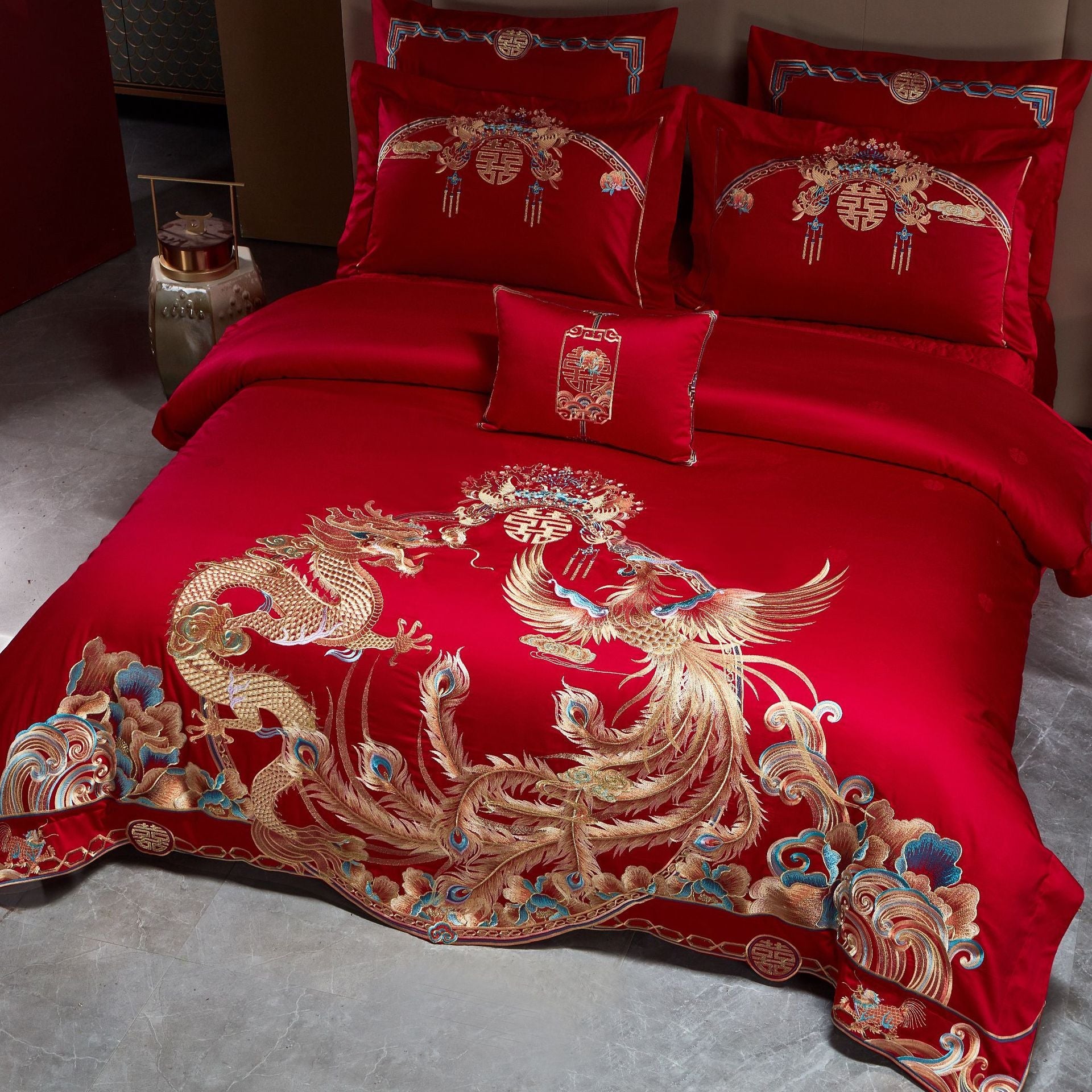 Red bedspread with gold dragon and phoenix design on a bed in a room.