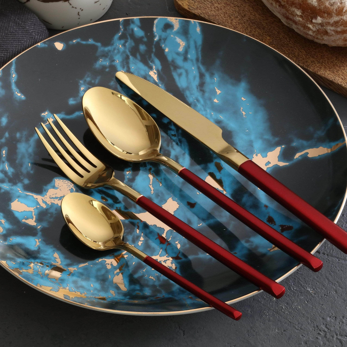 Gold cutlery with red handles on a blue marbled plate
